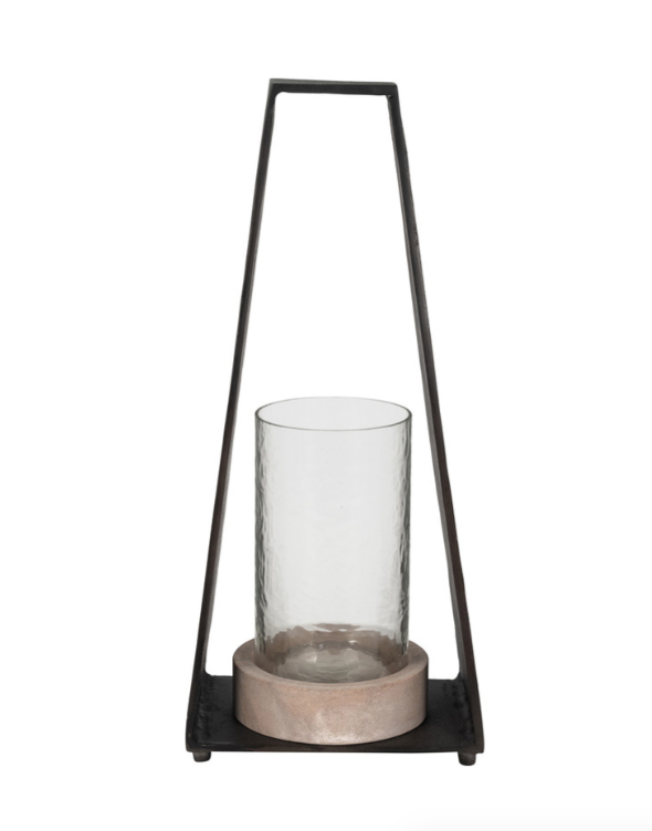 A black metal and sandstone hurricane candle holder with a clear glass base supporting a pillar candle.