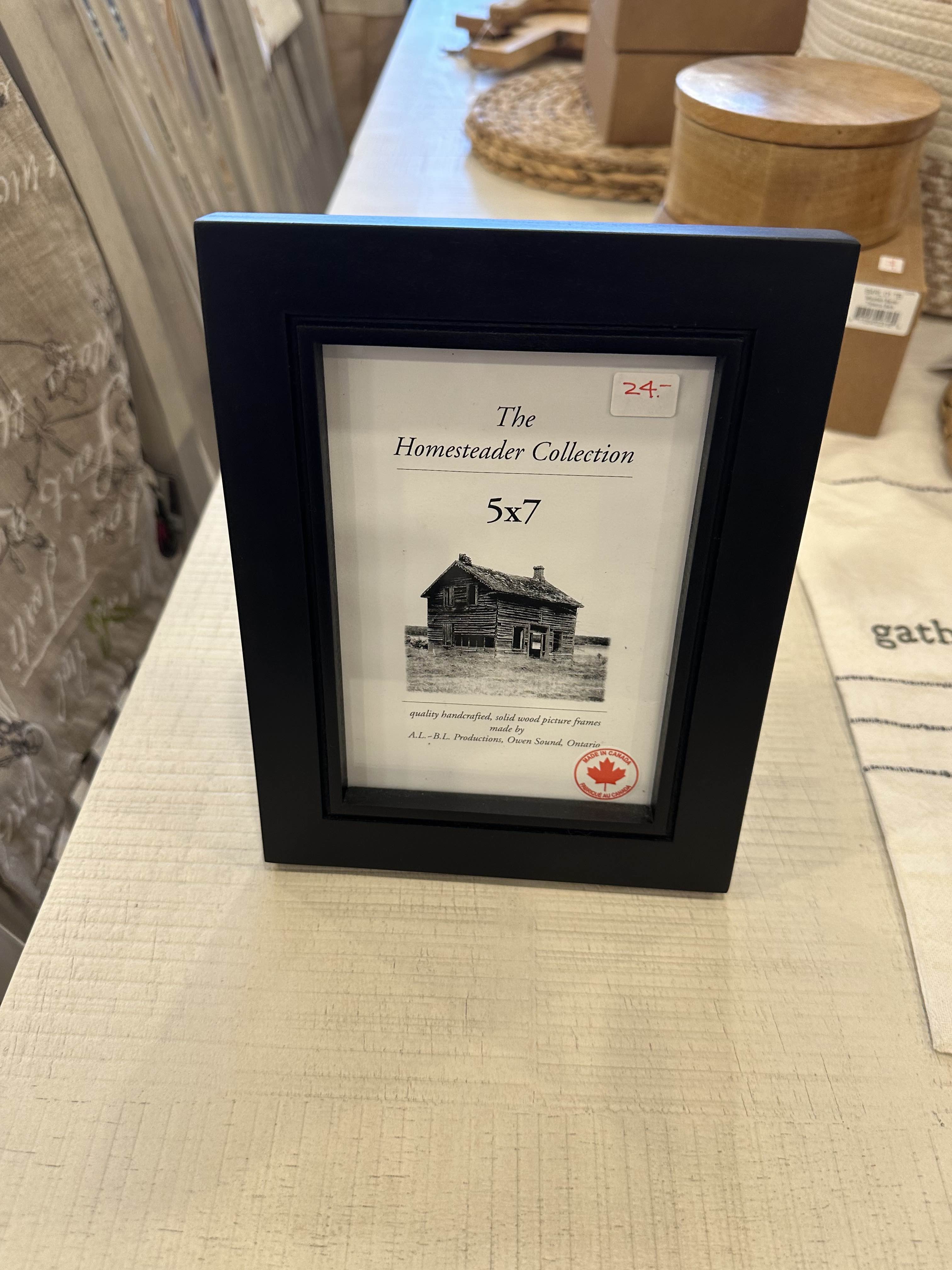 A black 5 x 7 picture frame with a clear display window showcasing a label that reads 'The Homestead Collection'