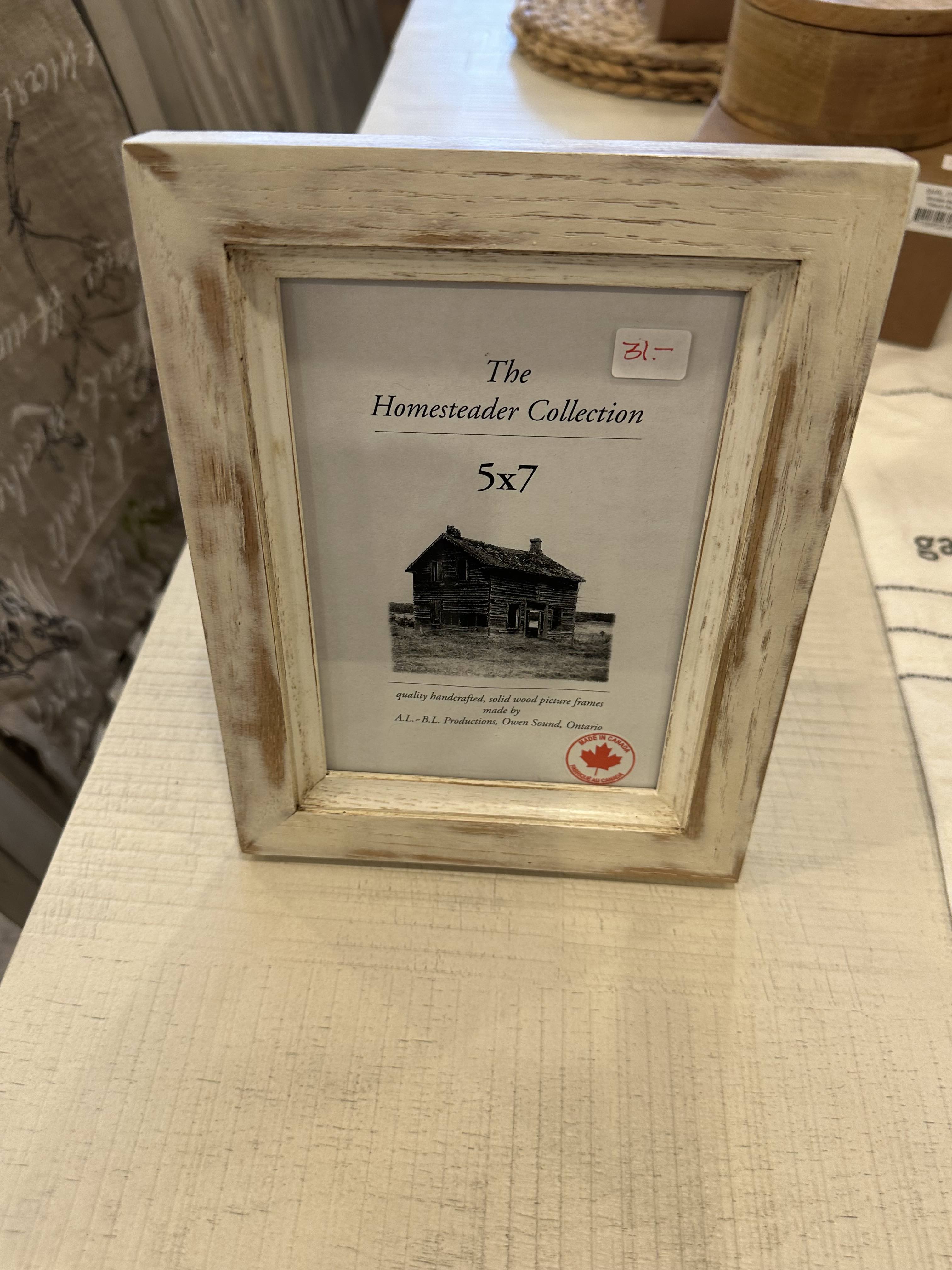 A 5x7 picture frame with a white distressed finish, displaying a label that reads 'The Homestead Collection 5x7'.
