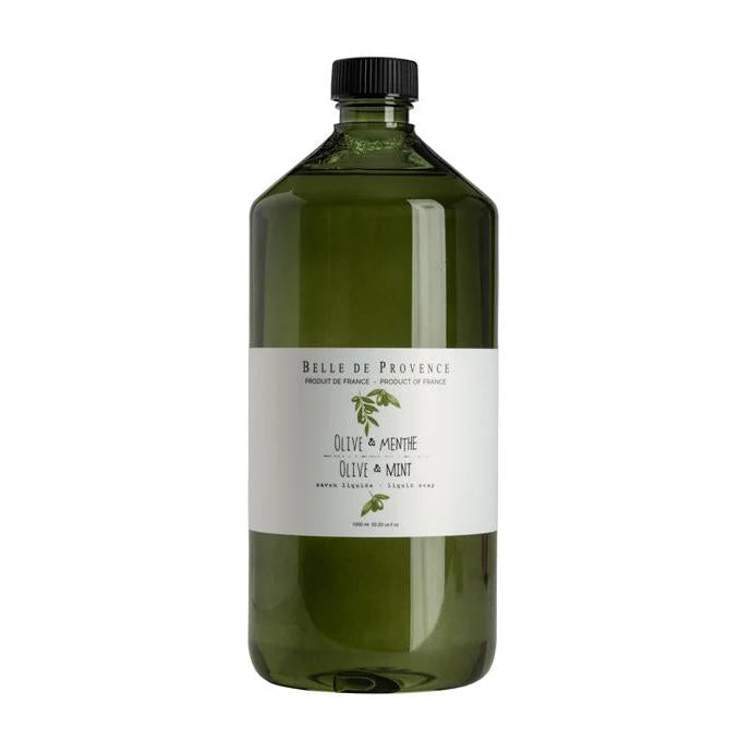 A clear glass bottle of Belle De Provence liquid soap with a label that reads 'OLIVE & MINT' and has a green cap.