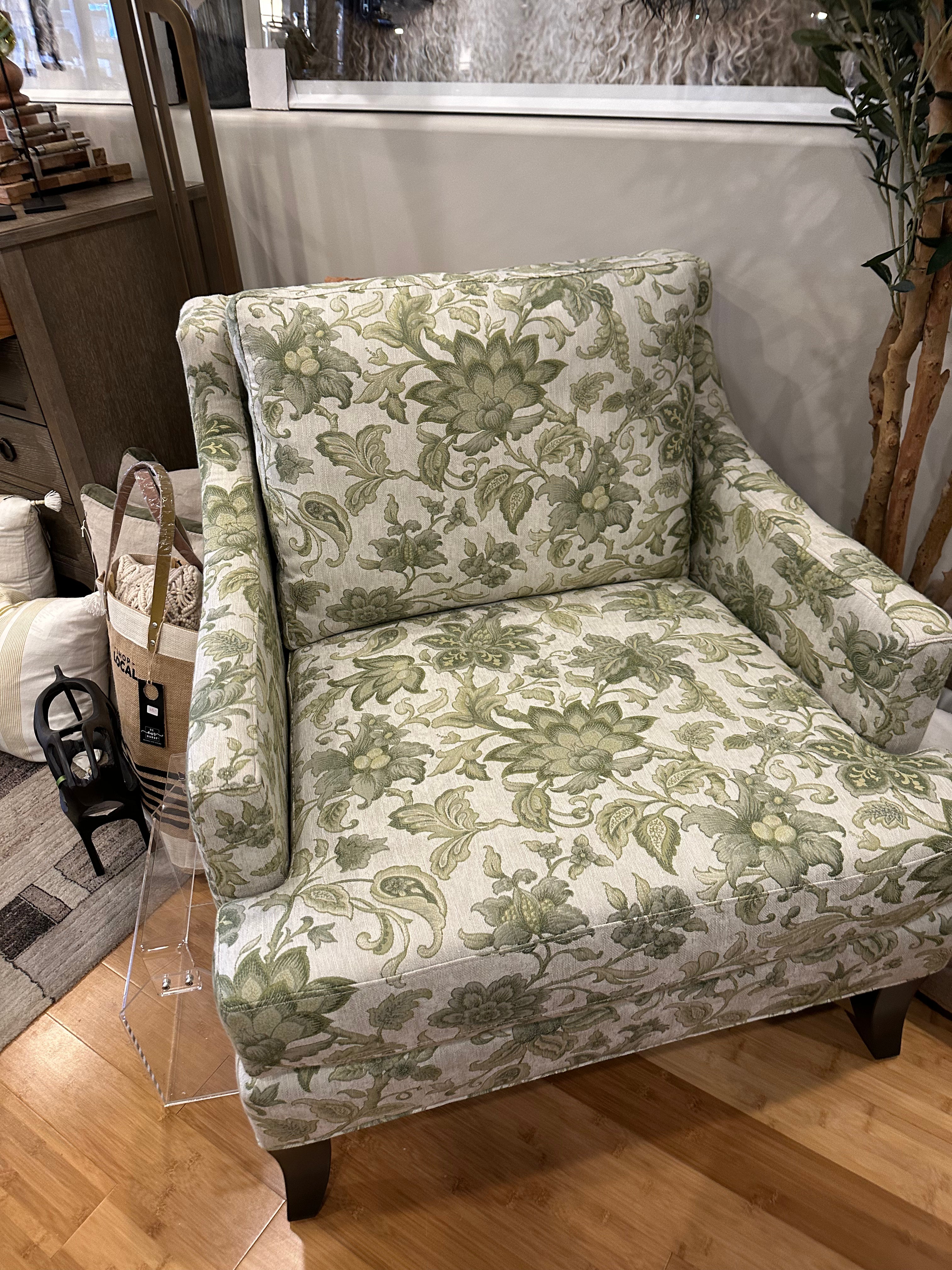A floral patterned chair with a beige, green, and white color scheme, upholstered in a specific fabric.