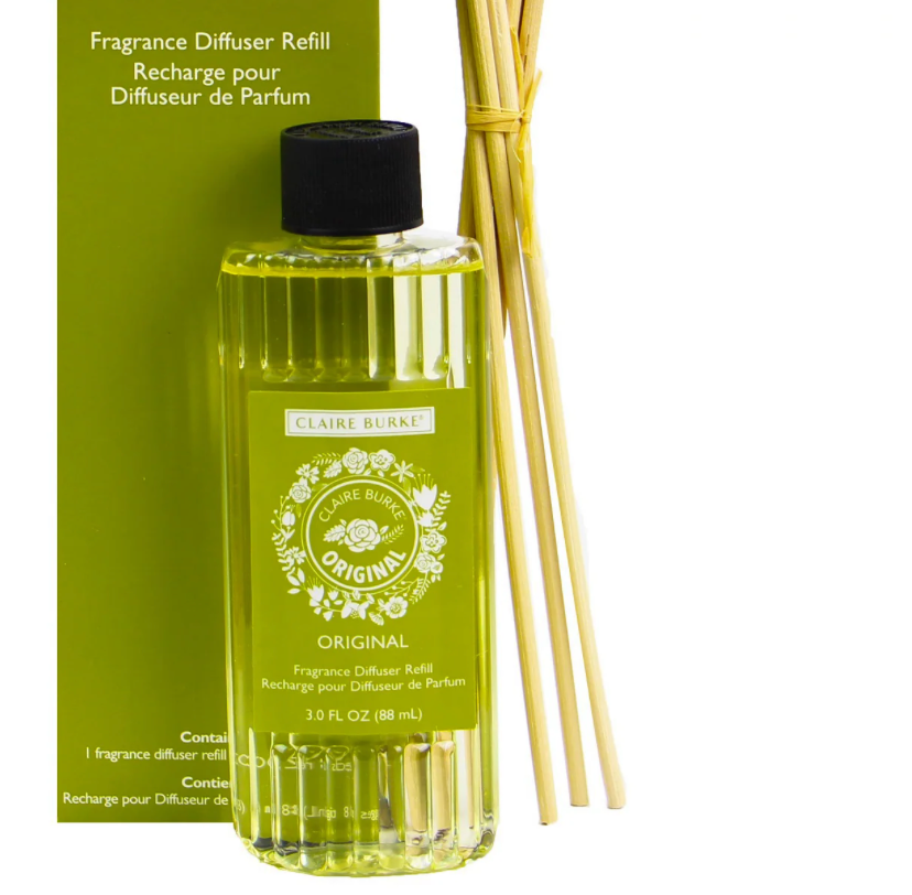A fragrance diffuser refill bottle with a label reading 'Original' from Claire Burke, accompanied by several reeds for diffusion.