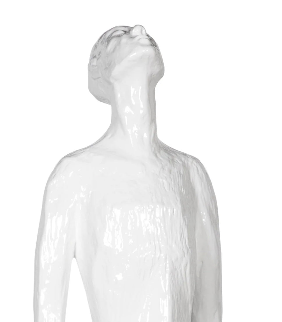 A white sculpture of a figure with a long neck and legs, looking upwards.