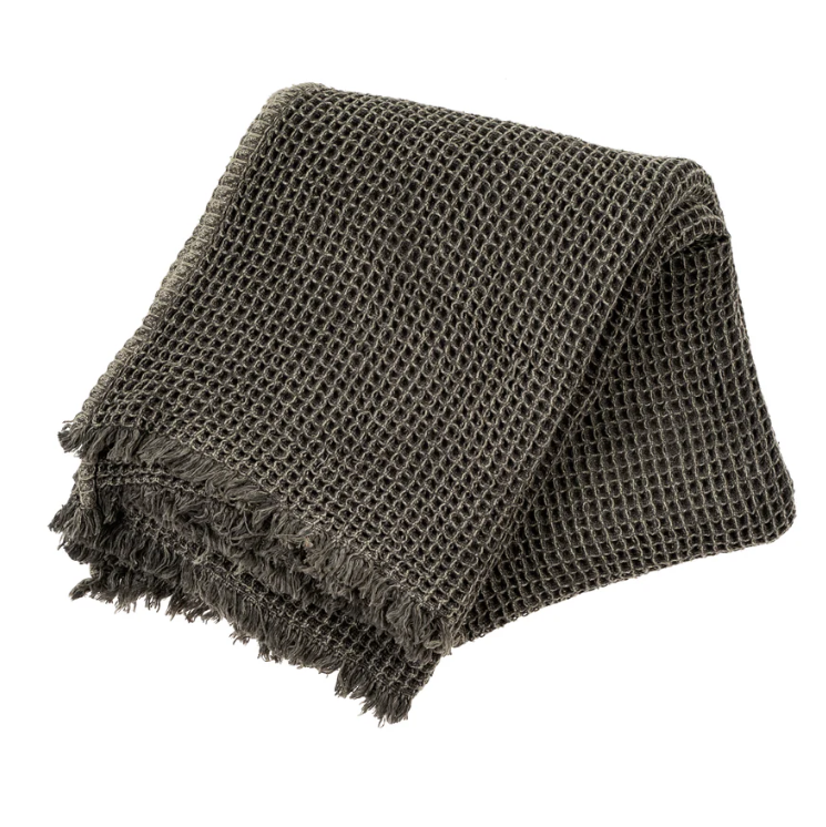 A dark grey waffle textured throw with a fringed edge, displayed on a white background.