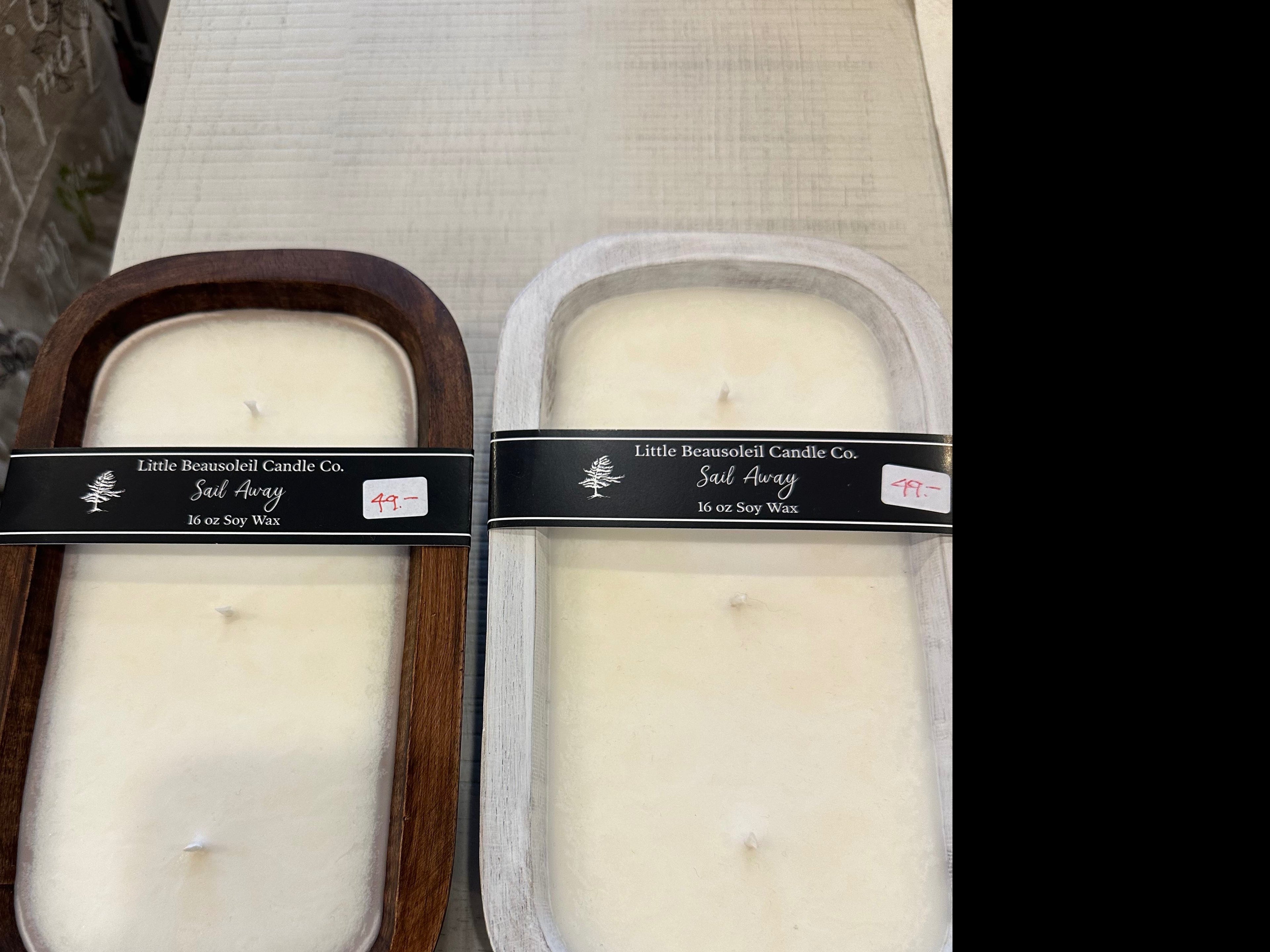 Two candles with wooden lids, one in front view and the other in side view, displaying the brand label 'LB Dough Bowls - Sail Away'.