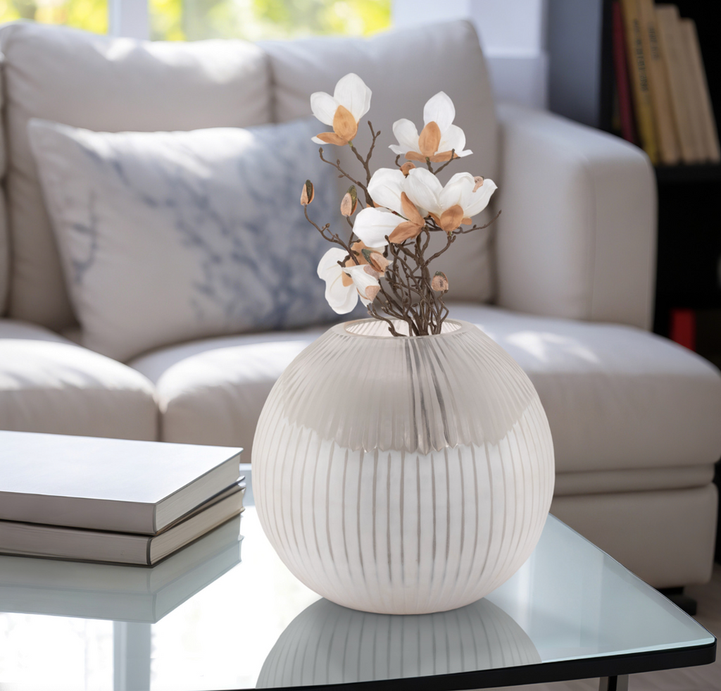 Decorative vase with flowers on a glass table in a living room setting