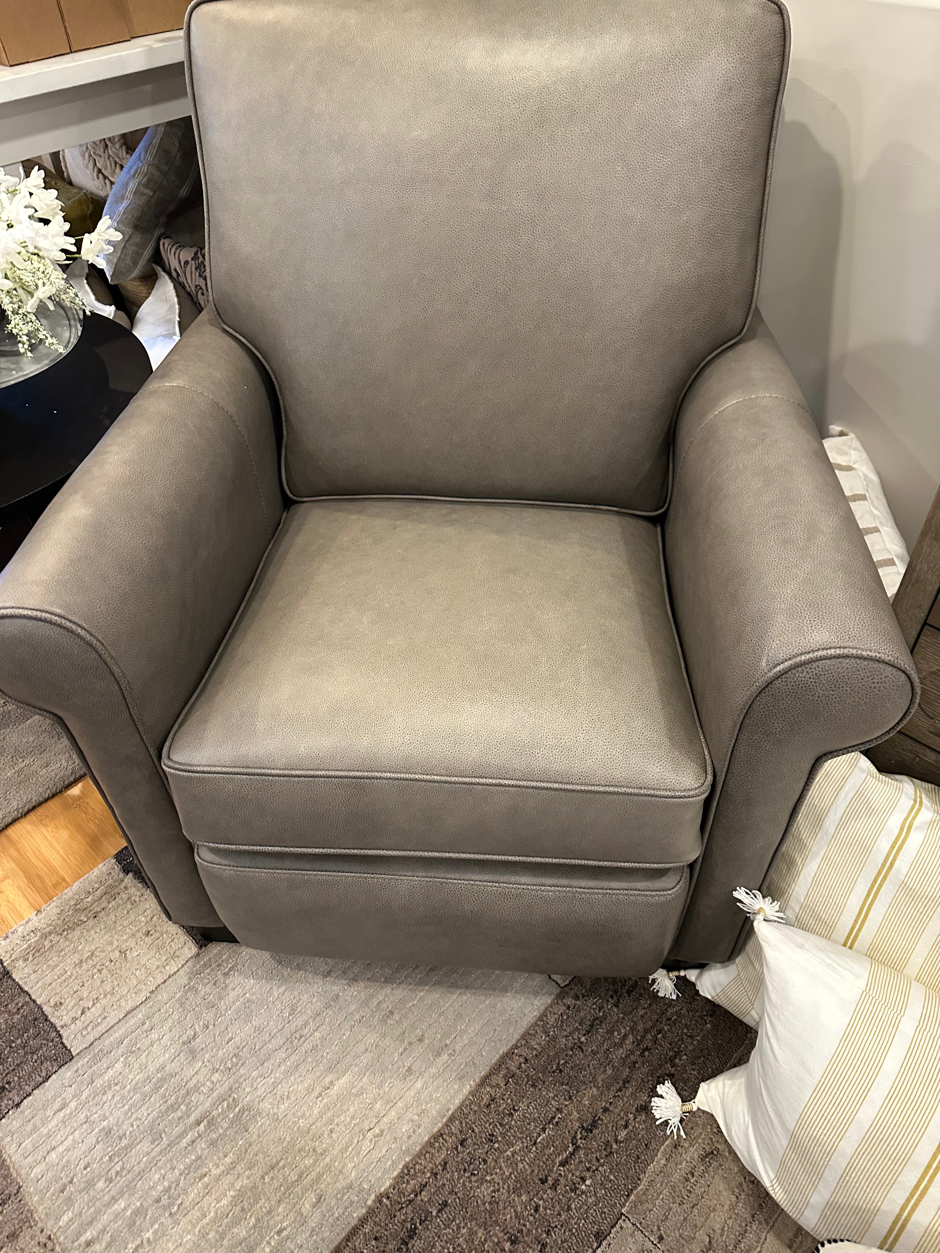 A gray leather power reclining leather chair with a high backrest, seated on a show floor.