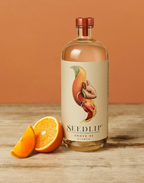 Bottle of citrus Seedlip Grove 42 on a wooden surface with oranges, against a brown background