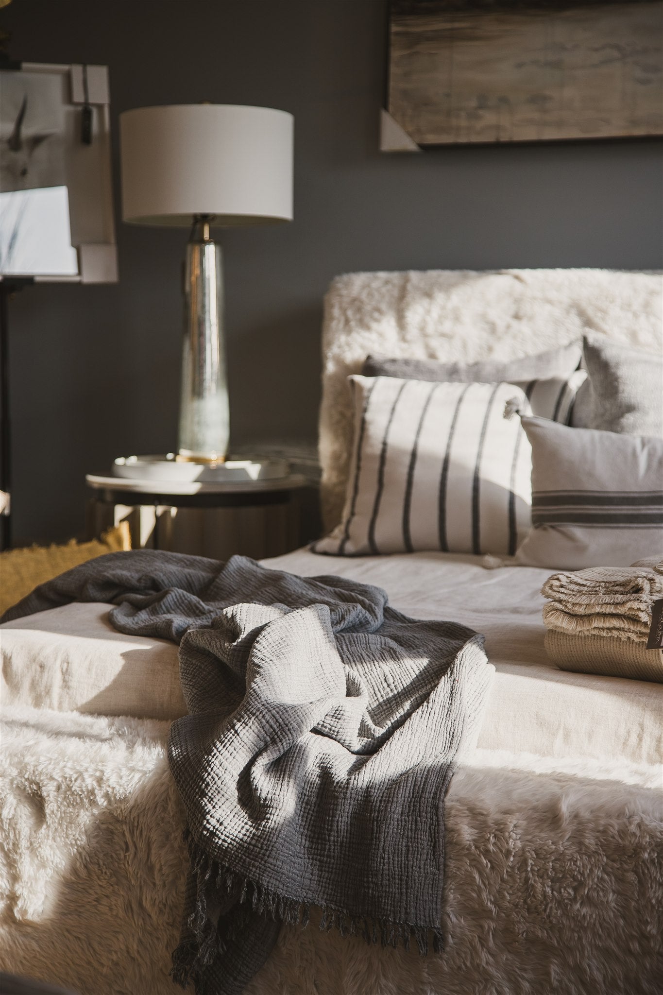 Cozy bedroom with a bed, lamp, blankets, throws and decorative pillows. 