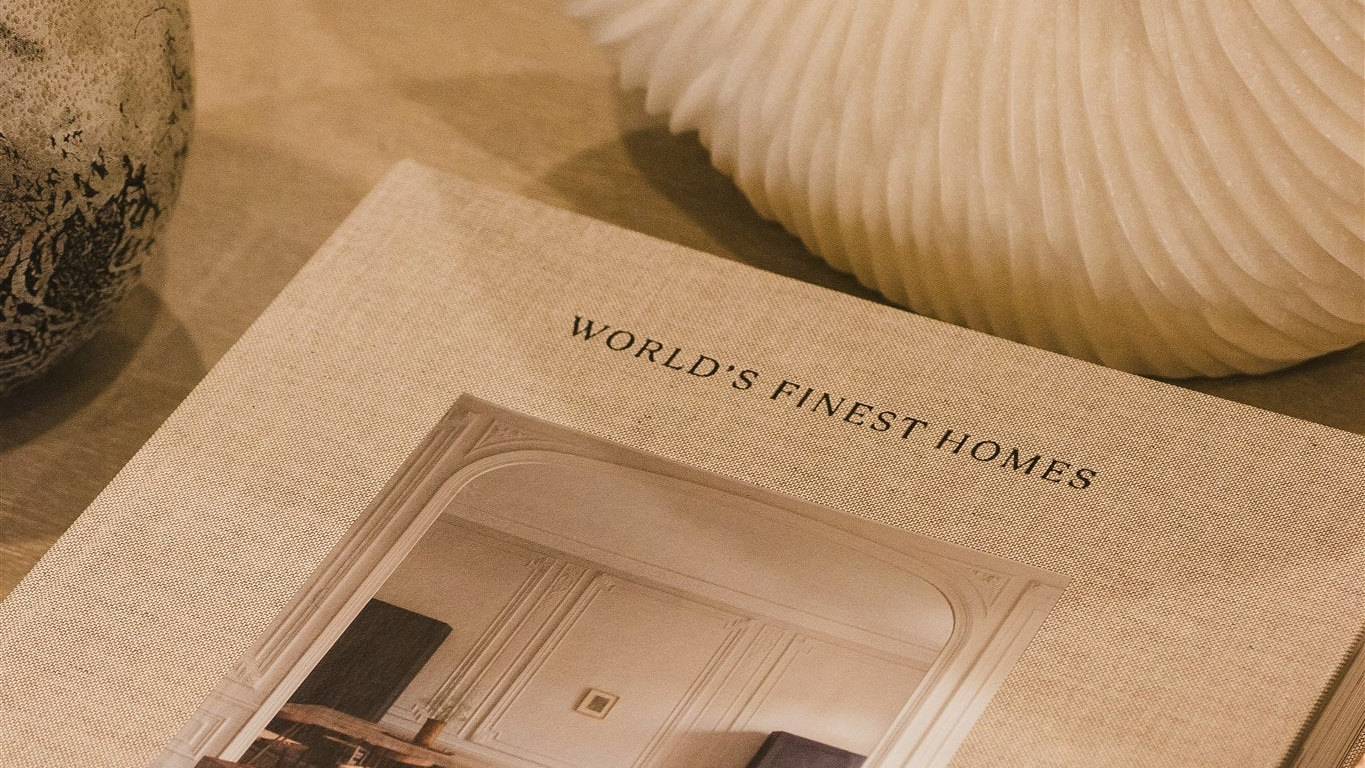 Book titled 'World's Finest Homes' on a wooden surface with decorative items.