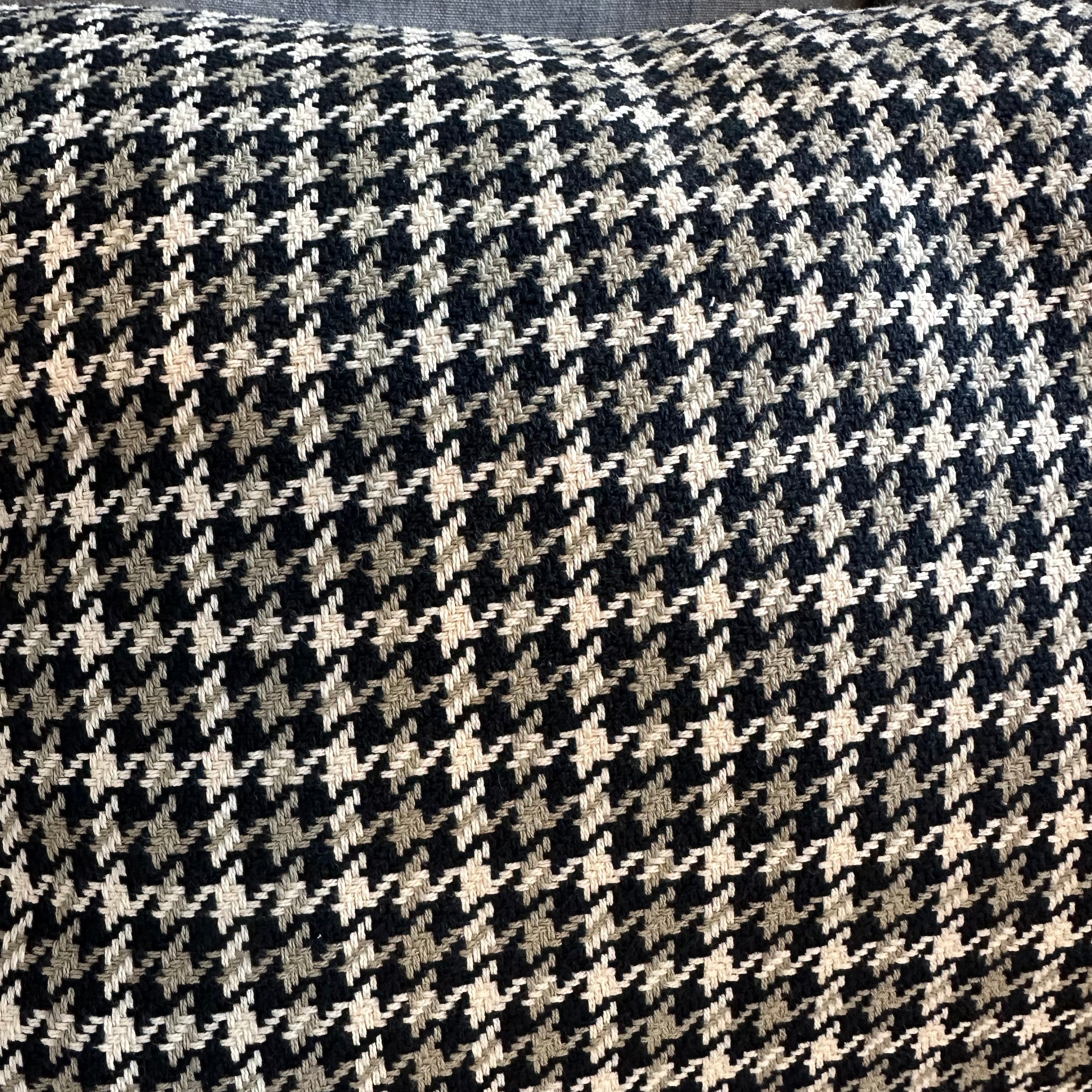 Close-up of houndstooth pattern fabric cushion in black, white and beige.