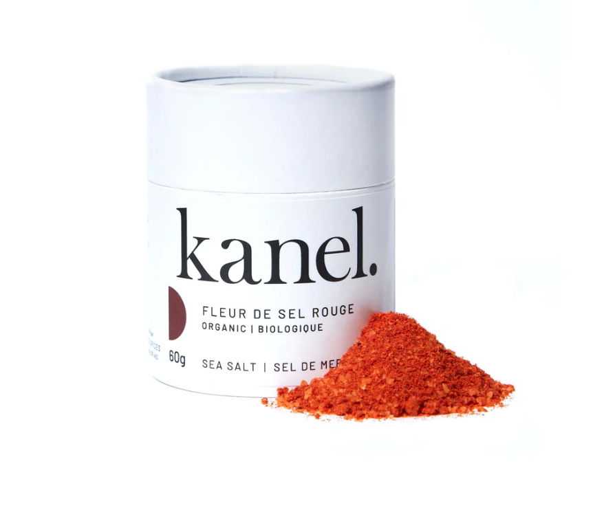 White cylindrical package of Kanel Fleur de sel rouge with a small pile of red seasoning. 