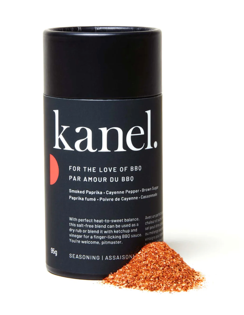A black cylindrical container labeled 'kanel. FOR THE LOVE OF BBQ' with a small pile of brown seasoning mix in front of it, indicating the product is a salt-free seasoning blend.
