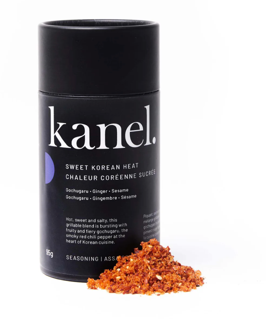 Black cylindrical package of Kanel Sweet Korean Heat seasoning with a pile of spices beside it. 