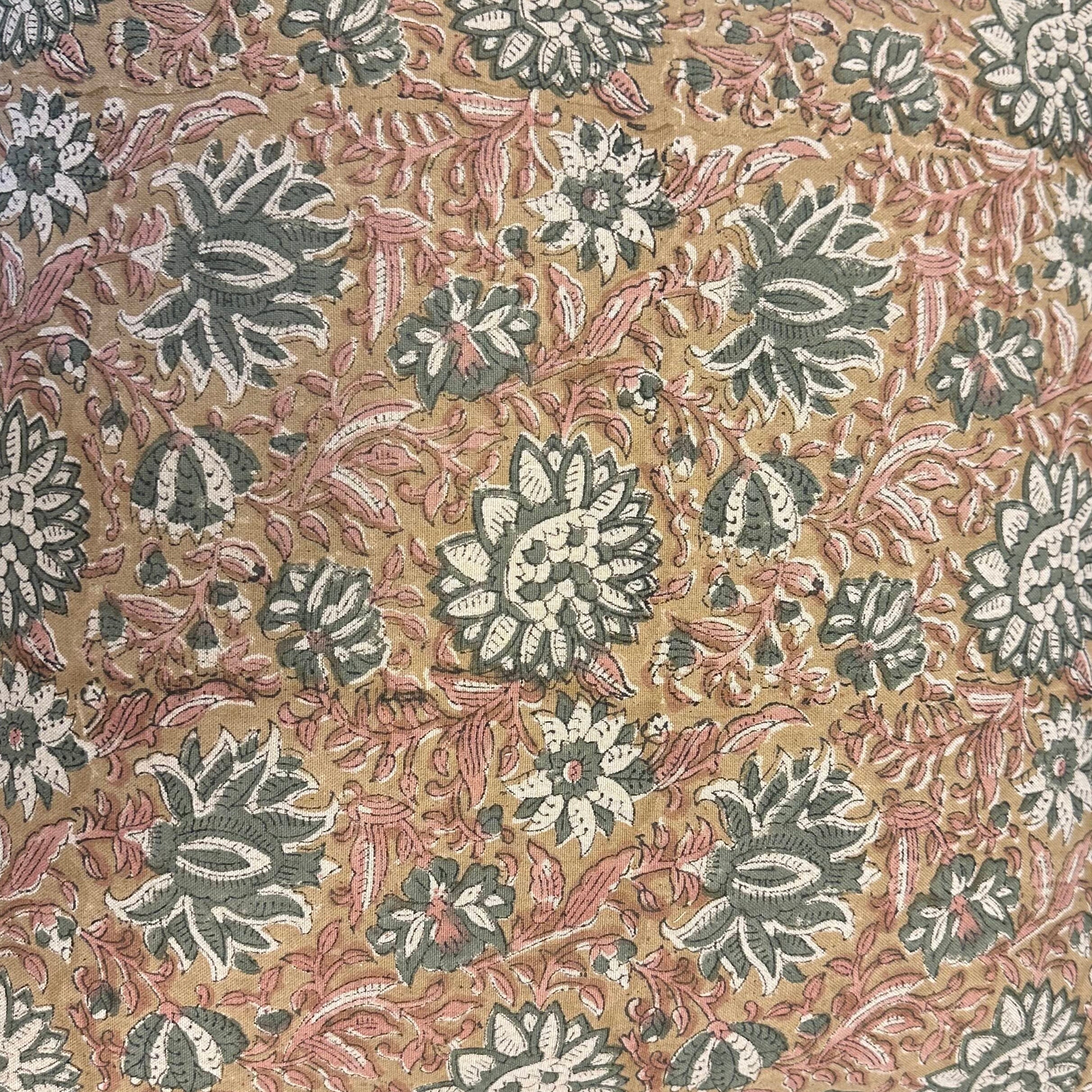 Patterned fabric with floral and leaf designs on a beige cushion