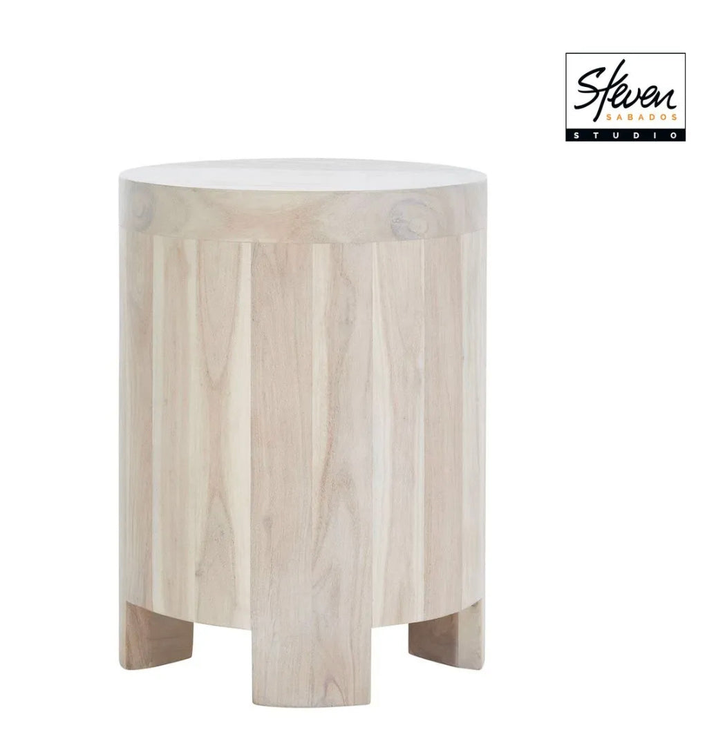 Whitewashed acacia wood side table with a cylindrical top and three-legged base, isolated on a white background with the Steven Sabados brand logo in the corner.