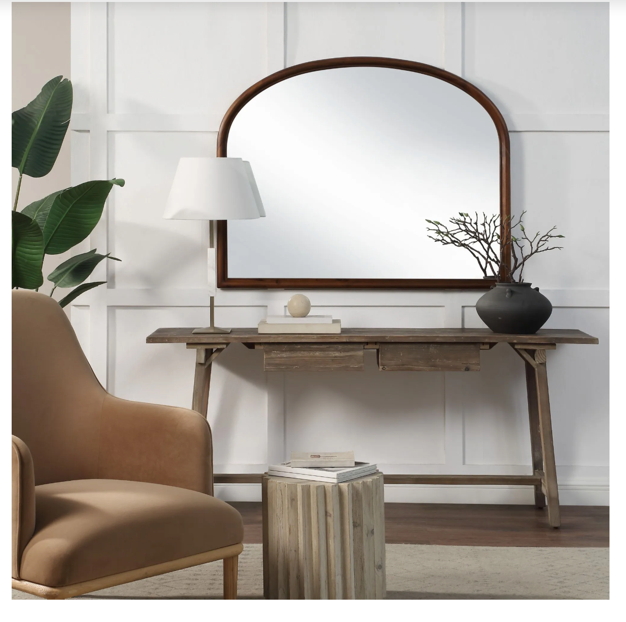 Wooden console table with mirror, lamp, and decor items in a room setting.