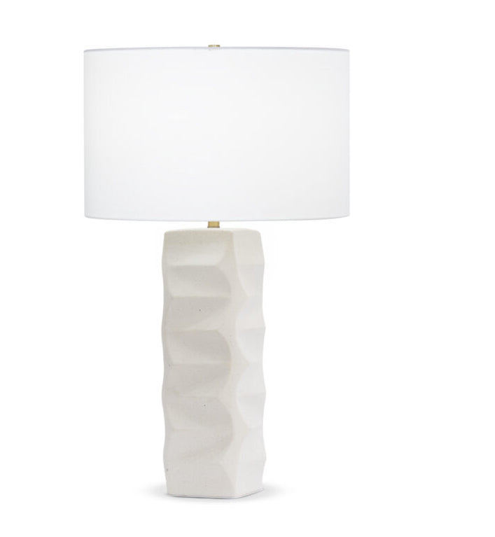 A modern art-inspired ceramic table lamp with a textured drum base and a beige cotton lampshade.