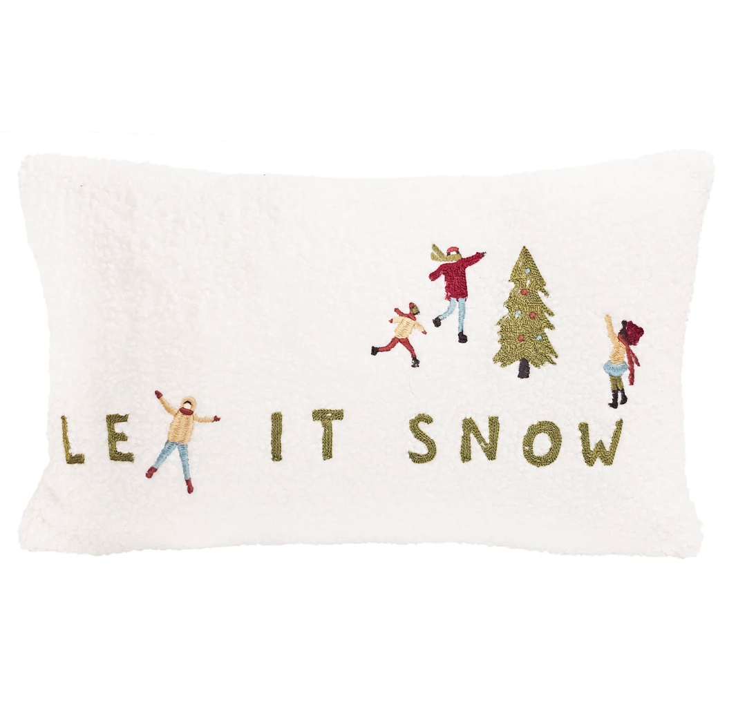 Decorative pillow with embroidered design of people and a tree, featuring the text 'LET IT SNOW'.