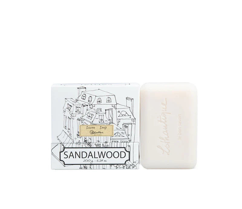 A white box of Lothantique bar soap with a drawing of a cityscape and labelled with the scent Sandalwood, beside a white bar of soap. 