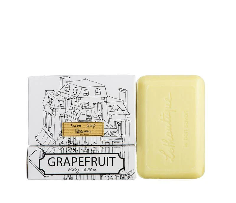 A box of Lothantigue Grapefruit soap with a sketch of city buildings on the front., beside a bar of light yellow soap. 