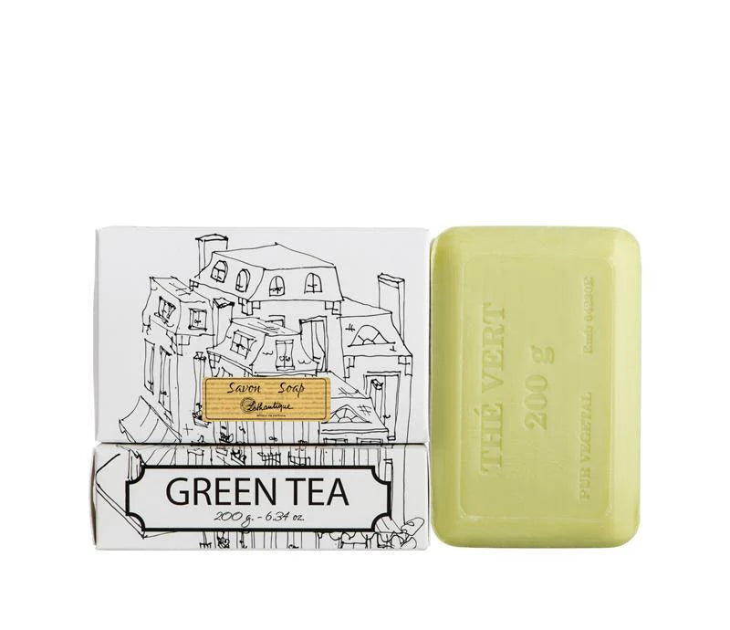 A white box of Lothantique bar soap with a drawing of a cityscape and labelled with the scent Green Tea, beside a light green bar of soap. 