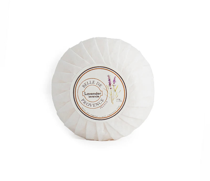 Round bar soap wrapped in white paper with a label that reads "Belle de Provence Lavender" with an image of a lavender plant. 