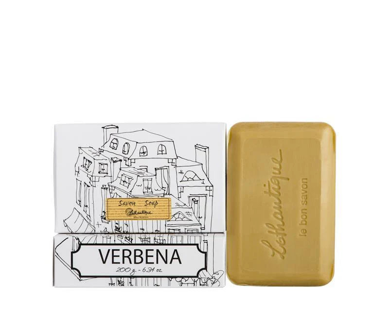 A white box of Lothantique bar soap with a drawing of a cityscape and labelled with the scent Verbena, beside a light brown bar of soap. 