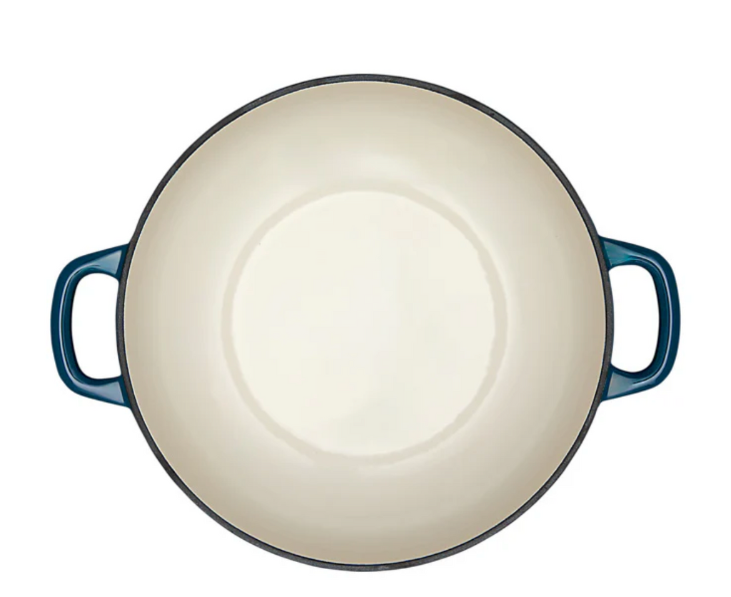 White interior of a blue enameled cast iron Dutch oven on a white background. 