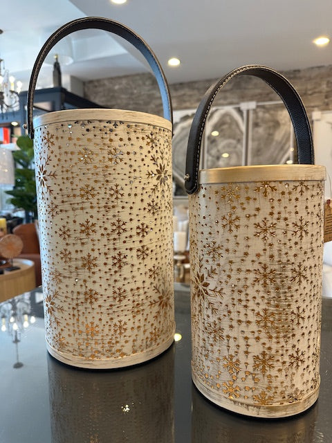 Two metal cylindrical baskets with decorative patterns on a reflective surface.