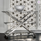 Modern stainless steel bar cart with geometric design in a room with decorative wall patterns.