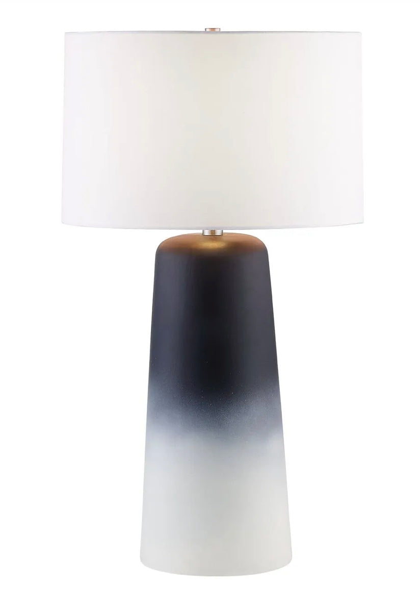 A table lamp with a white shade and a multi-colored base, transitioning from dark to light shades vertically.