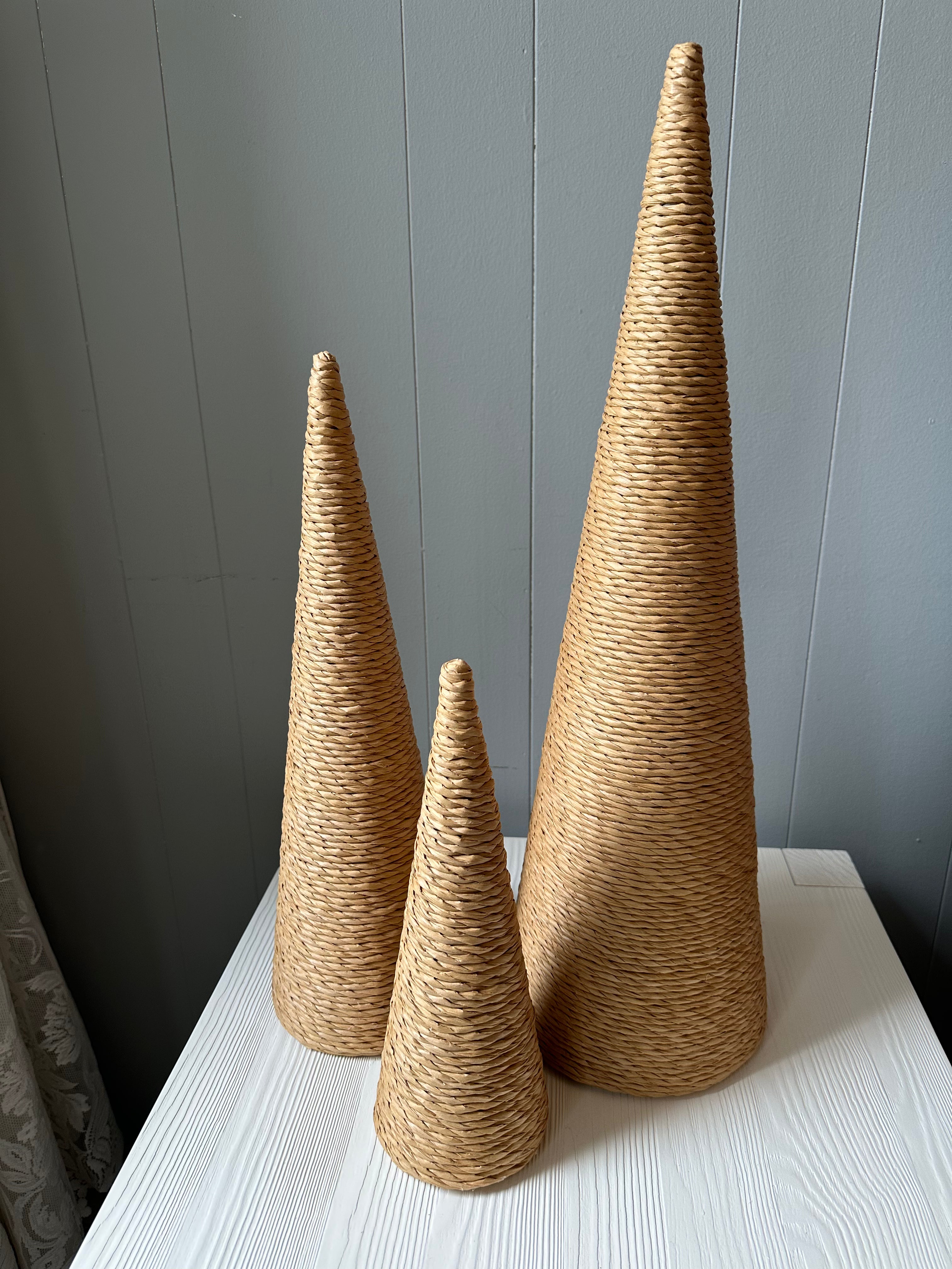 Three cones of differing heights resembling trees wrapped in brown twine. 