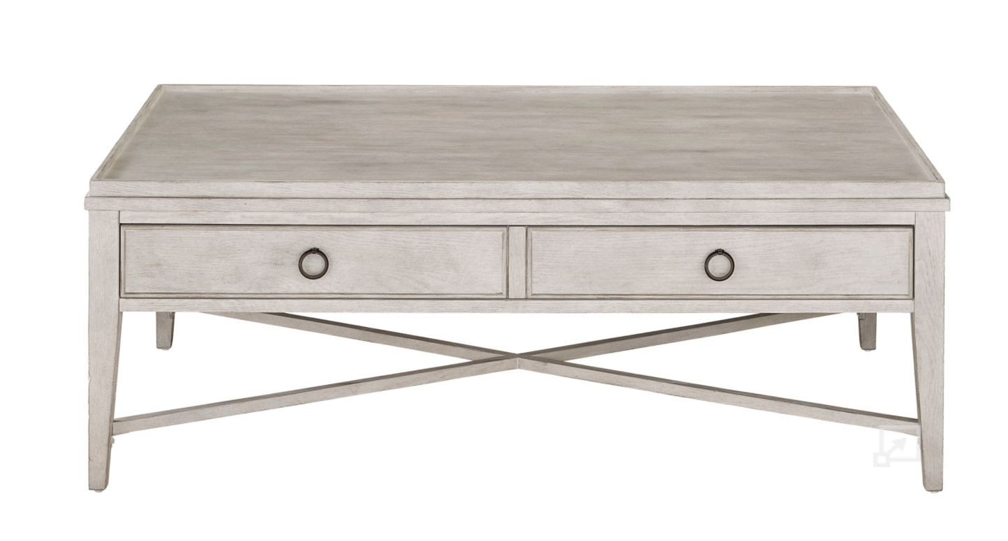Wooden white washed coffee table with drawers and criss-crossed base on a white background. 