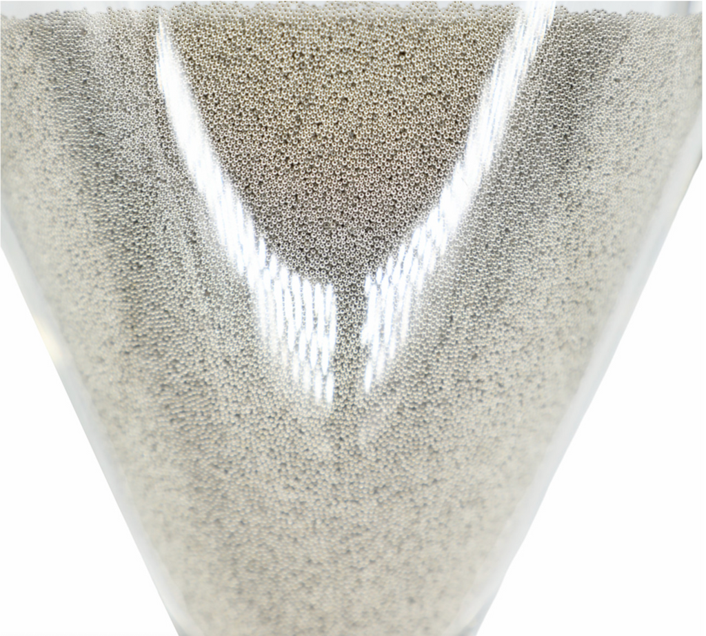 Close up of tiny silver balls in large silver hourglass. 