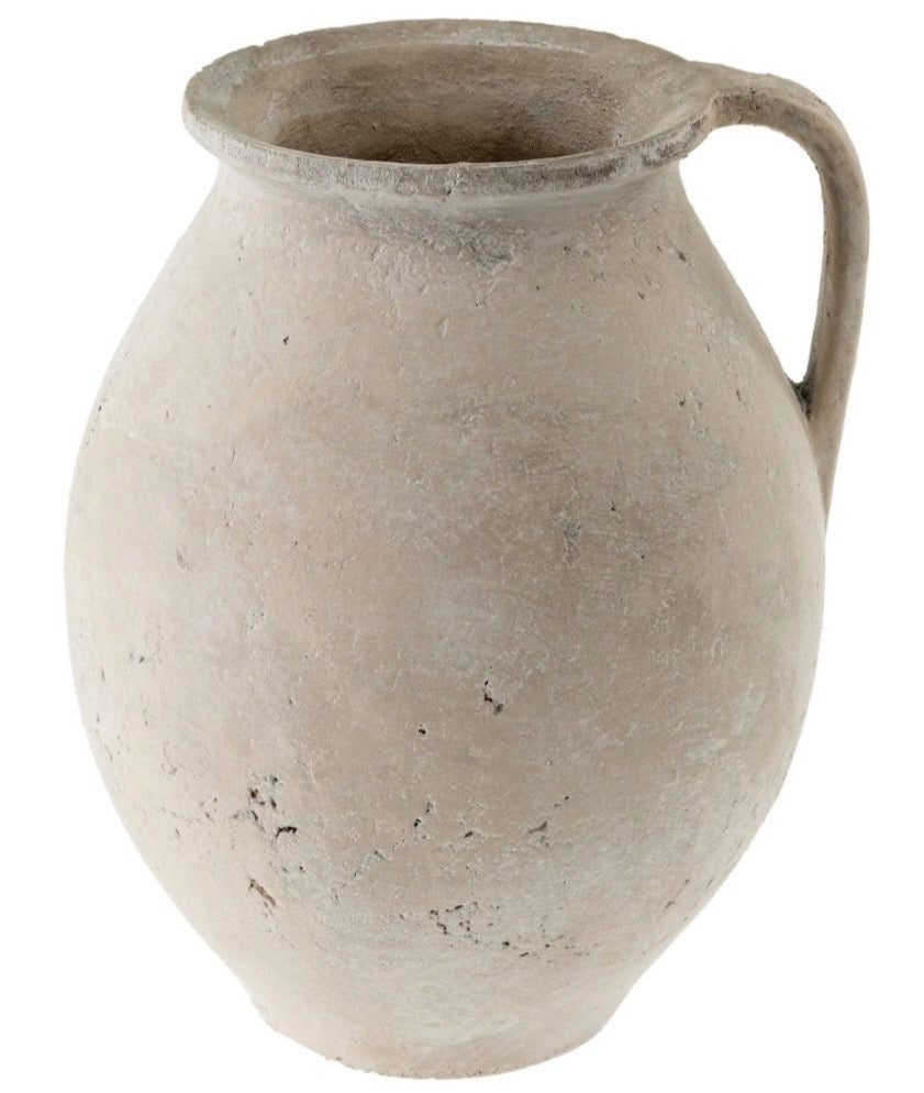 A cream-colored, textured ceramic pitcher vase with a handle.