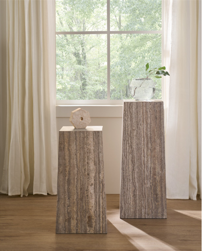 Two rectangular gray travertine finish tables with a minimalist design, pictured in a room setting with curtains and a plant in the background.
