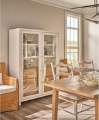 Dining room with wooden table, chairs, and a glass-fronted cabinet.