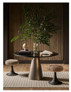 Round table with a vase of greenery and decorative items in a modern setting.