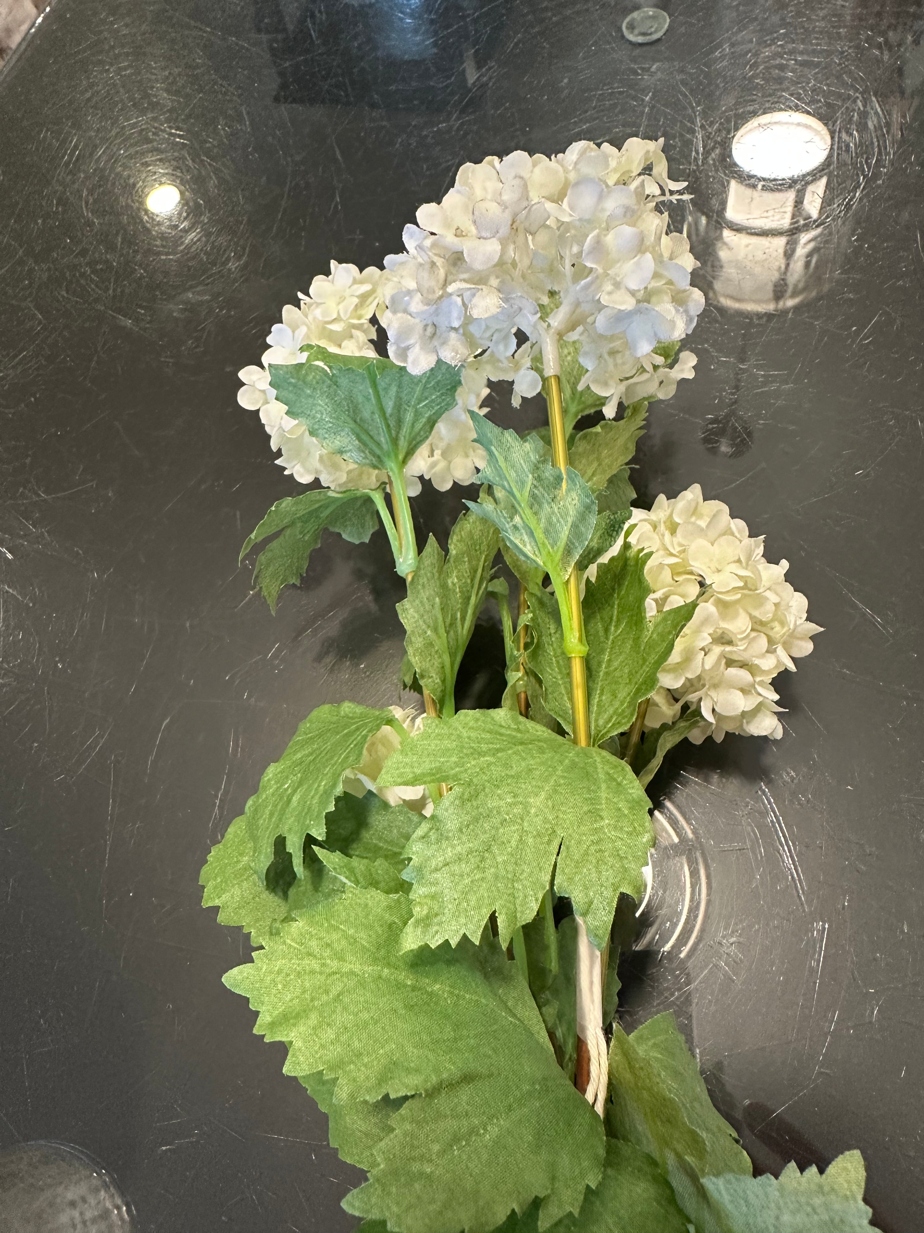 Faux Snowball bush floral on a dark table background. 