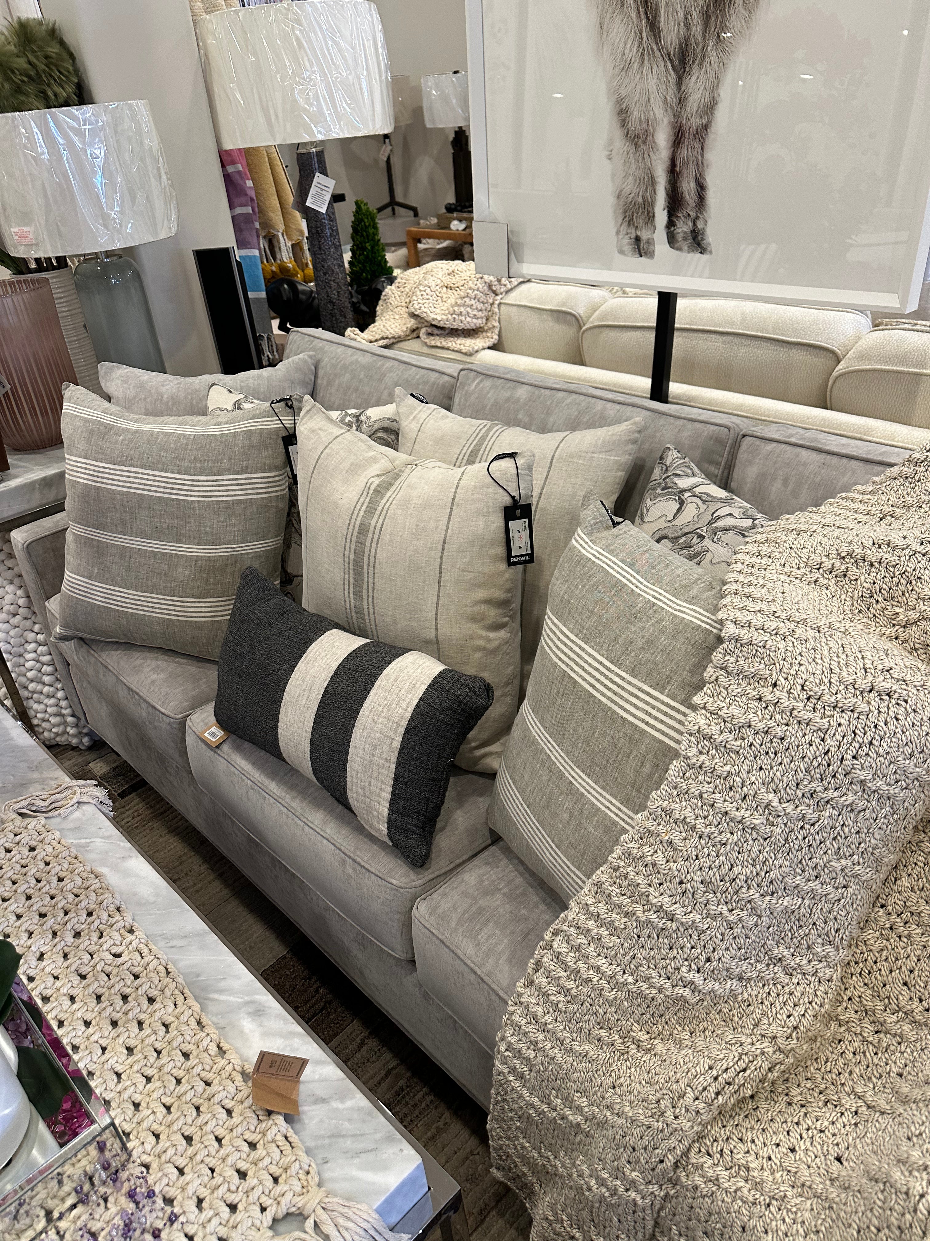 A sofa with multiple cushions arranged on it, featuring a mix of solid colors and striped patterns.