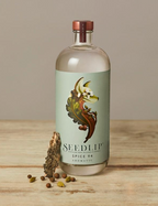 Bottle of Seedlip Spice 94 on a wooden surface with a neutral background