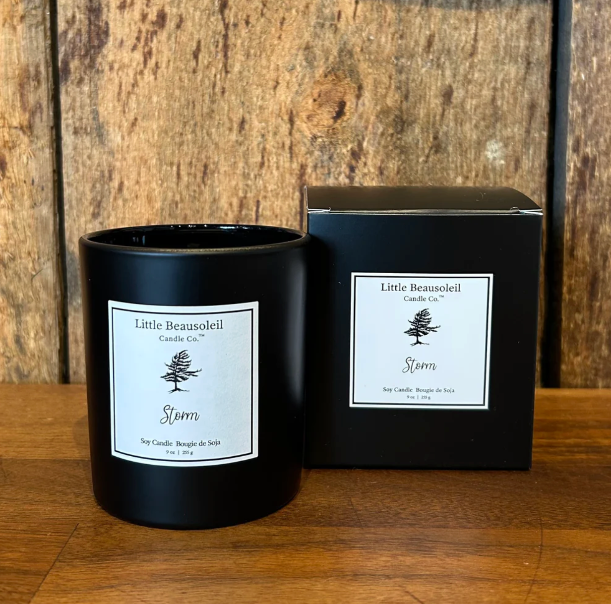 Black candle with 'Little Beausoleil' label next to its packaging on a wooden surface.