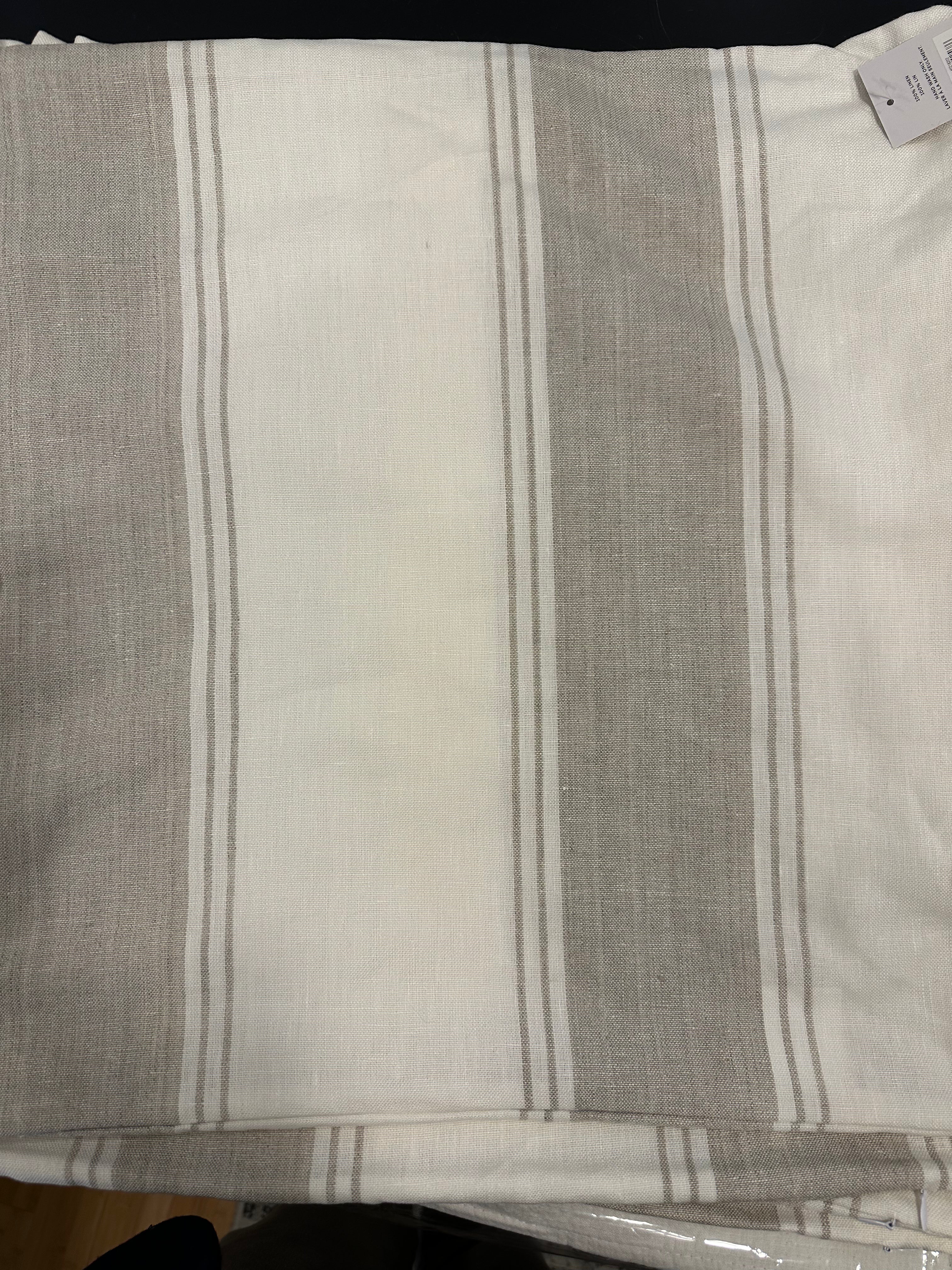 A folded striped linen cushion in beige and white colors.