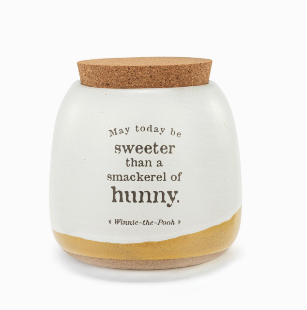 A white ceramic canister with a cork lid, featuring text from Winnie-the-Pooh and a honeycomb design at the bottom.