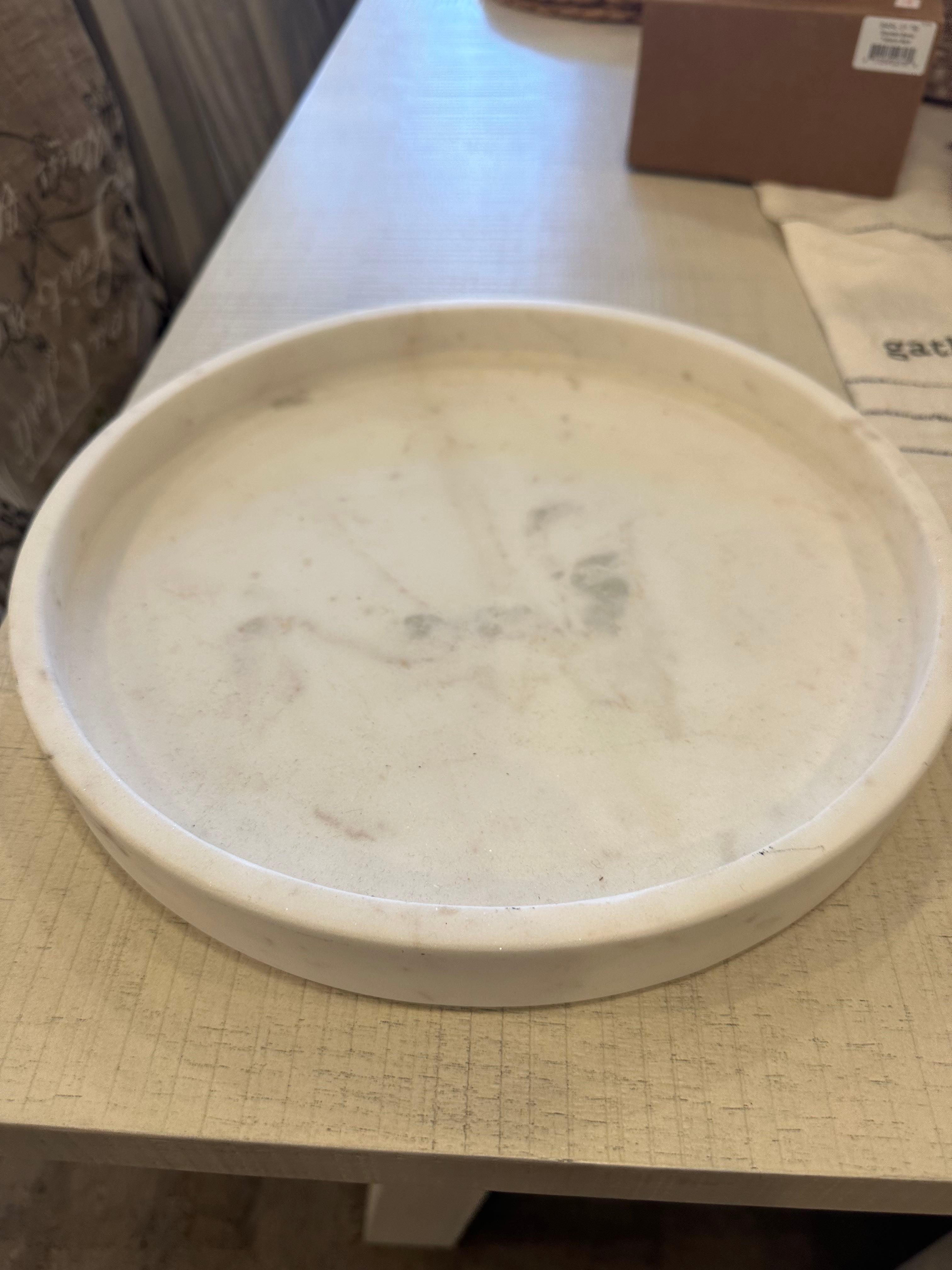 A round, white marble tray on a table.