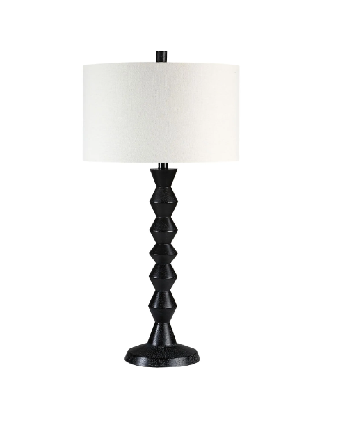 A black geometric-inspired table lamp with a white linen drum shade.