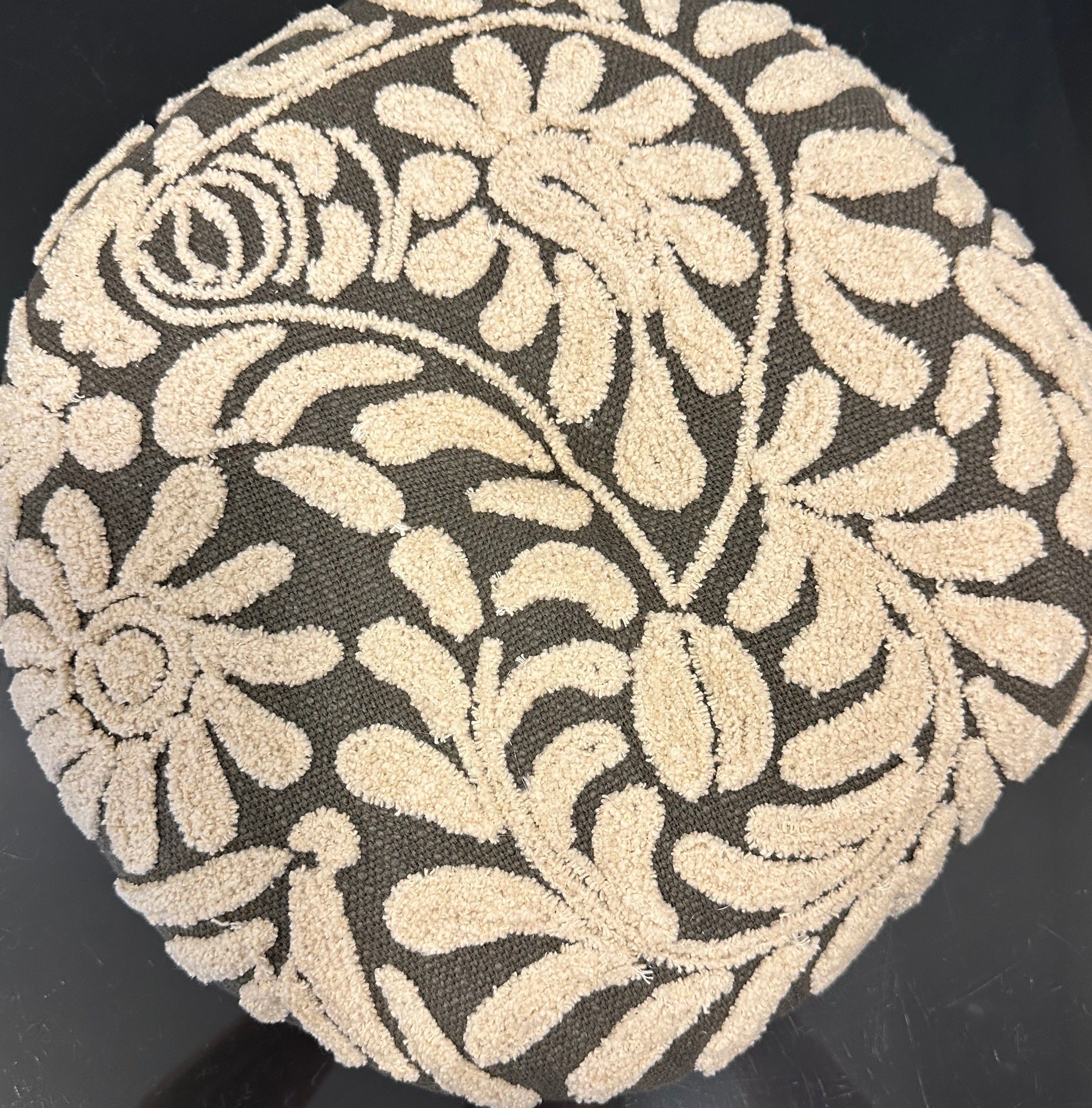 Decorative round pillow with floral pattern on a black background