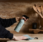Person holding a bottle labeled 'Expert's Choice' over a wooden surface with kitchen utensils.