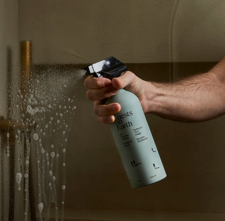 Person holding a bottle labeled 'Nest of Earth' in a bathroom setting.